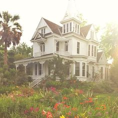 a large white house surrounded by trees and flowers