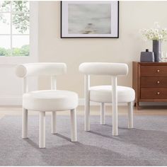 two white chairs sitting next to each other on a rug in front of a window