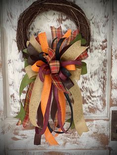 a wreath is hanging on the front door with ribbons attached to it's sides