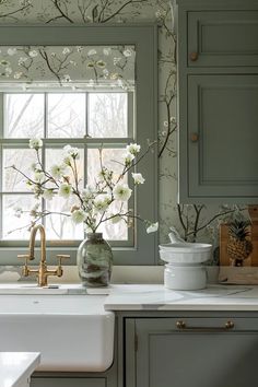 a vase with flowers sitting on top of a kitchen counter next to a sink and window