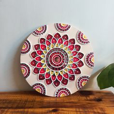 a decorative plate sitting on top of a wooden table next to a potted plant