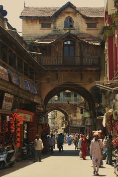 an old city street with people walking around and shops on the side walk in front of it