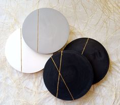 three black and white plates sitting on top of each other next to some straw grass