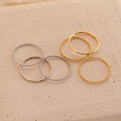 Our Skinny Stacking Rings are the simple and minimalist essentials for creating a dainty, multilayered finger stack that'll be the envy everyone around you. Their slightly textured finish adds a unique touch to the stack, as the trio features a ball, twist, and smooth band. Material: High-Quality Solid 925 Sterling Silver Finish: Sterling Silver ∙ 18K Gold Dimensions: 1mm This listing is for a set of 3 rings: 1 SOLID ring, 1 TWISTED ring, and 1 BEADED ring SKU: RR-RR051 Sizing Guide Rings are cr Minimalist Essentials, Layering Diamond Necklaces, Twisted Ring, Multiple Rings, Silver Diamond Ring, Beaded Ring, Stacking Ring Set, Twist Ring, Rings Set