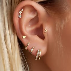 a woman wearing gold ear piercings with hearts and stars on the side of her ear