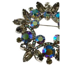 Luxuriously crafted , this 2.75" diameter, 0.5" h Vintage  Rhinestone Crystal Wreath Brooch displays the vibrant Aurora Borealis for a classic, elegant look.  The setting is solid silver-tone and has a secure functioning pin. Perfectly preserved in its condition, this circular faceted pin will bring a unique touch to any outfit. AB bead treatments were invented by Swarovski back in 1956, in partnership with Christian Dior. Silver Jeweled Brooches For Formal Occasions, Formal Silver Jeweled Brooches, Silver Jeweled Brooches For Party, Silver Jeweled Brooches For Evening, Silver Jeweled Party Brooches, Crystal Round Brooch For Party, Round Crystal Brooch For Party, Round Rhinestone Brooches For Formal Occasions, Silver Crystal Round Brooches