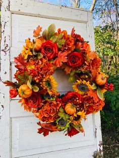 an orange wreath with sunflowers and pumpkins is hanging on the front door