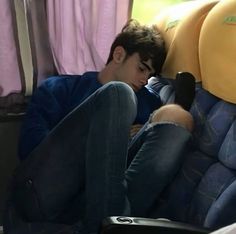 a man sleeping on a bus seat with his feet propped up against the armrest