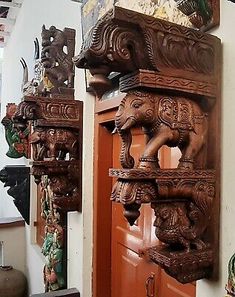 an elephant carved wooden door handle on the side of a building with other decorations hanging from it's sides