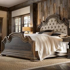 a large bed sitting inside of a bedroom on top of a wooden floor next to a window