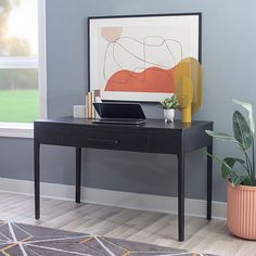 a black desk with a laptop on it next to a potted plant in front of a window