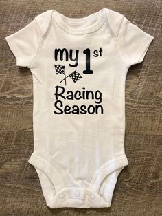 My 1st Racing Season This listing is for one (1) white bodysuit  with black lettering on the front. Available in short sleeve.  Available Sizes:  Newborn 3 Month 6 Month  9 Month  12 Month I hand make each bodysuit, no two will be exactly the same, please allow 3-7 business days for production. Please email me with any questions.  Material: White 100% Cotton  Care Instruction: Inside out wash Tumble Dry Do not bleach Do not iron directly onto the design Do not dry clean Want to see more, check u White Cotton Sports Bodysuit, White Short Sleeve Bodysuit With Graphic Print, Fitted White Onesie With Graphic Print, White Casual Bodysuit For Sports, Sporty White Cotton Bodysuit, White Casual Sports Bodysuit, White Cotton Sporty Bodysuit, White Fitted Onesie With Graphic Print, Sports Cotton Onesie With Short Sleeves