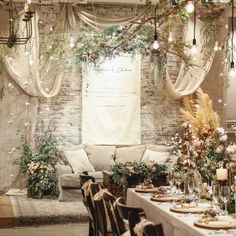 a table set up for a wedding reception with flowers and greenery on the wall