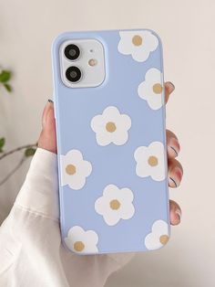 a person holding up a blue phone case with white flowers on the front and gold dots on the back