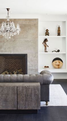 a living room filled with furniture and a chandelier hanging from the ceiling over a fire place