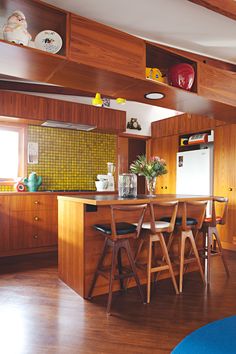 a kitchen with wooden cabinets and chairs in the center island, next to a dining room table