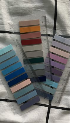 there are many different colors of paper on the bed sheet with rulers next to them