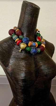 Look at the vibrant colors in this bold, chunky, heavy and oversized beaded African - Tibetan beaded two strand statement necklace! This features African recycled glass, Yoruba brass, Zebu bone disks and beads, Moroccan resin, Nepalese glass, metal daisy spacers, Tibetan resin and Tibetan fancy inlaid beads, tribal metal spacers and fancy silver tone etched or stamped beads. Adjusts from 17-20" with gold tone hardware, a lobster claw clasp, and a 3" extender chain with a ethnic heart pendant. Pl Eclectic Multicolor Beaded Necklaces With Large Beads, Eclectic Multicolor Beaded Necklace With Large Beads, Traditional Colorful Large Beads, Unique Multicolor Wooden Beads, Multicolor Wooden Beads, Unique Multicolor Spacer Beads, African Inspired Fashion, Inspired Fashion, African Inspired