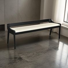 a black and white bench sitting on top of a tile floor next to a window