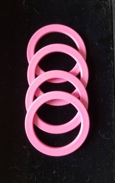 three pink rings sitting on top of a black surface