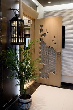 a plant in a pot sitting next to a wooden door with decorative designs on it