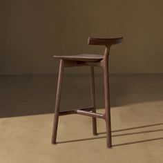 a wooden stool sitting on top of a floor next to a brown wall with shadows