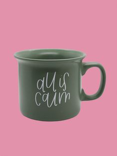 a green mug with the words'duls calm'printed on it against a pink background