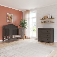 a baby crib and dresser in an empty room with orange paint on the walls