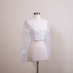 "Romantic puff sleeve lace topper | light ivory bridal lace topper | bridal lace jacket | bridal separates Light ivory wedding dress topper with built in tulle sash at the back. The color is light ivory. It is fully lined with soft tulle fabric. It features satin wrapped buttons at the back. Please note this item is made to order and the lead time is 4 to 5 weeks. We have small, medium, large and x-large sizes available. Size XXL can be made to order but please note that XXL size is not returnable or exchangeable Size Small: Shoulder width: 14.5\" Upper arm circumference: 11.5\" Bust: 34\" US size: 0 ~ 4 UK size: 2 ~ 6 Size Medium: Shoulder width: 15\" Upper arm circumference: 12.5\" Bust: 35.5\" US size: 6 ~ 8 UK size: 8 ~ 10 Size Large: Shoulder width: 16\" Upper arm circumference: 13.5\ White Long Sleeve Wedding Dress With Lace Sleeves, Delicate Lace Top For Wedding Night, Feminine White Wedding Dress, Long Sleeve Lace Trim Wedding Dress, White Tulle Wedding Dress With Lace Sleeves, Elegant Lace Top For Wedding Night, Elegant Tulle Wedding Dress With Lace Sleeves, Feminine Lace Top For Spring Wedding, Elegant Scalloped Lace For Brides