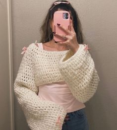 a woman taking a selfie in front of a mirror wearing a sweater and jeans