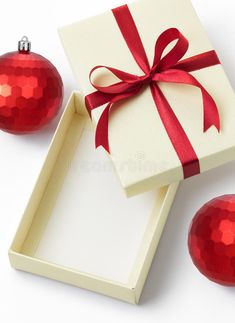 two red ornaments and a white box with a red ribbon