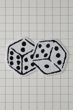 two black and white dices on top of a tile floor in front of a tiled wall