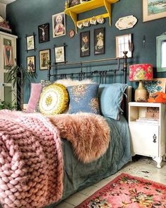 a bedroom with blue walls and pictures on the wall above the bed, along with rugs