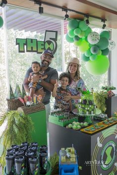 a man and two children are standing in front of a table with green decorations on it