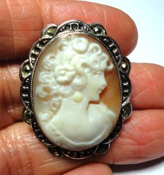 Cameo brooch pin is a Vintage antique Italian cameo pin in a solid sterling silver frame with marcasites on the mounting. Genuine vintage carved shell cameo in solid sterling silver frame mounting with marcasites adding sparkle and embellishing the ornate cameo frame. This lovely vintage cameo treasure, is a a genuine hand carved shell cameo, and it can be worn as a brooch or pendant. The cameo is signed by the artist on the back. There is a loop for a chain or ribbon on the back. The back frame Carved Brooches For Formal Occasions, Antique Carved Brooches For Formal Occasions, White Cameo Brooch For Formal Occasions, White Cameo Brooches For Formal Occasion, Antique Carved Brooches For Weddings, Antique White Brooch For Formal Occasions, Ornate Carved Oval Brooches, Ornate Oval Carved Brooches, Antique White Formal Brooch