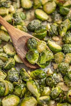 brussel sprouts are being cooked in a pan with a wooden spoon