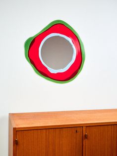 a wooden cabinet sitting next to a white wall with a mirror on top of it