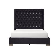 an upholstered bed with black velvet headboard and foot board, in front of a white background