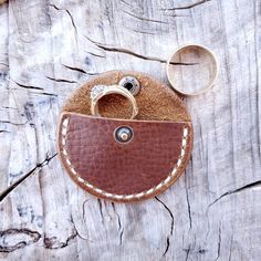 two wedding rings in a brown leather case next to a pair of scissors on a piece of wood