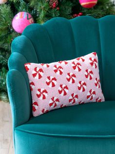 a green chair with a red and white knitted pillow sitting on top of it