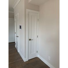 an empty room with two white doors and hard wood flooring on either side of the door