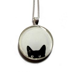 a black and white cat in a round glass pendant