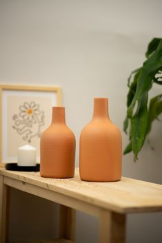 two orange vases sitting on top of a wooden table