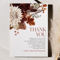 a thank you card with flowers and leaves on it next to a feathery object