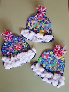 three hats made out of felt and cotton balls on top of a table next to scissors