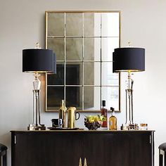 two lamps are sitting on top of a dresser in front of a mirror and other items