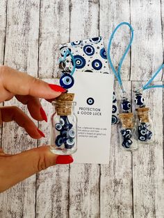 a hand holding a tiny bottle filled with blue and white beads next to two small bottles