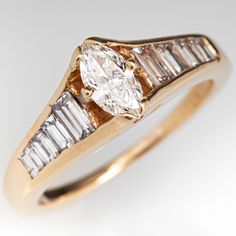 an engagement ring with three baguets and two diamonds on the side, set in yellow gold