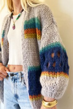 a woman is wearing a colorful sweater and jeans