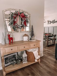 a wooden table with christmas decorations on it and a mirror hanging above the table in front of it